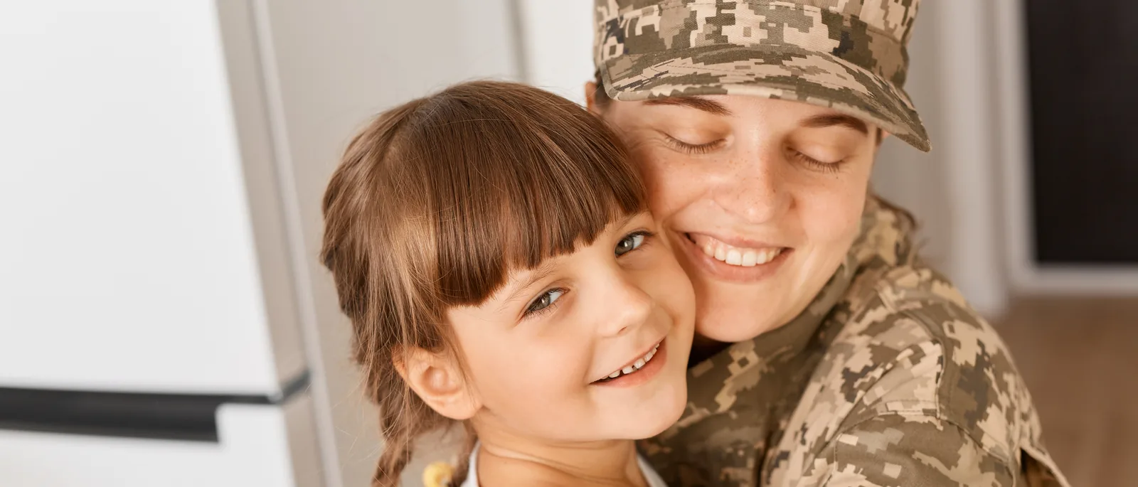 Servicewoman in camouflage at home among moving boxes